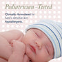 Newborn baby wearing a striped hat with text about pediatrician testing and hypoallergenic formulation.