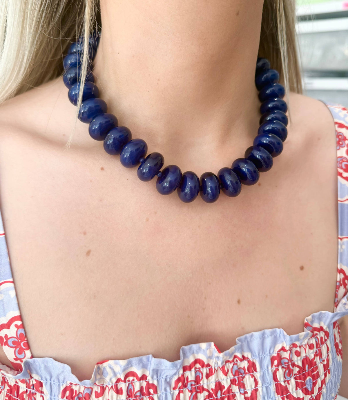 Chunky navy beaded necklace on model’s neck with gold clasp