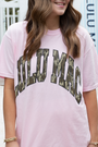 Person wearing a pink t-shirt with 'Lulu Mac' printed in camouflage text.