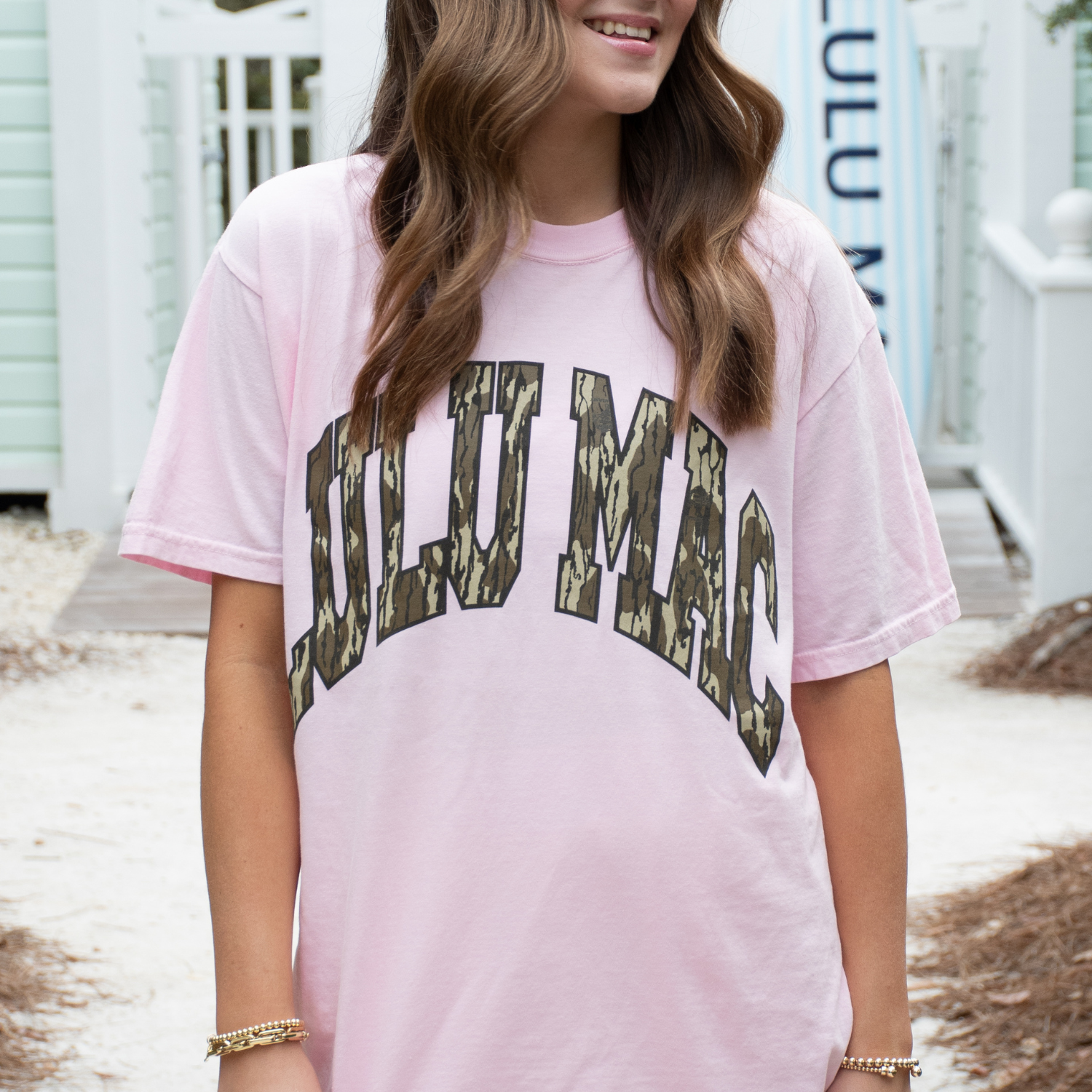 Person wearing a pink t-shirt with 'Lulu Mac' printed in camouflage text.