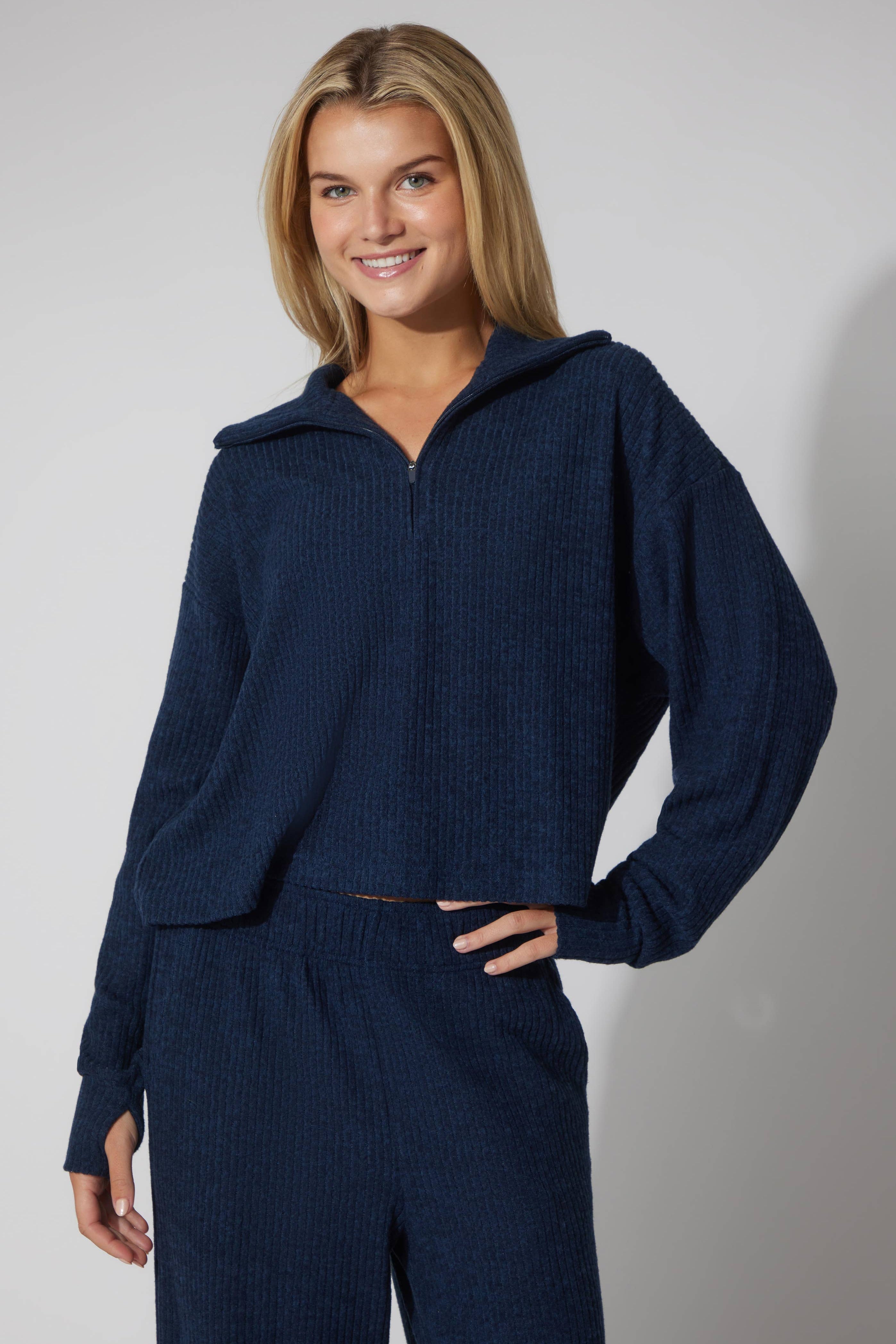Woman wearing a navy blue outfit against a plain background