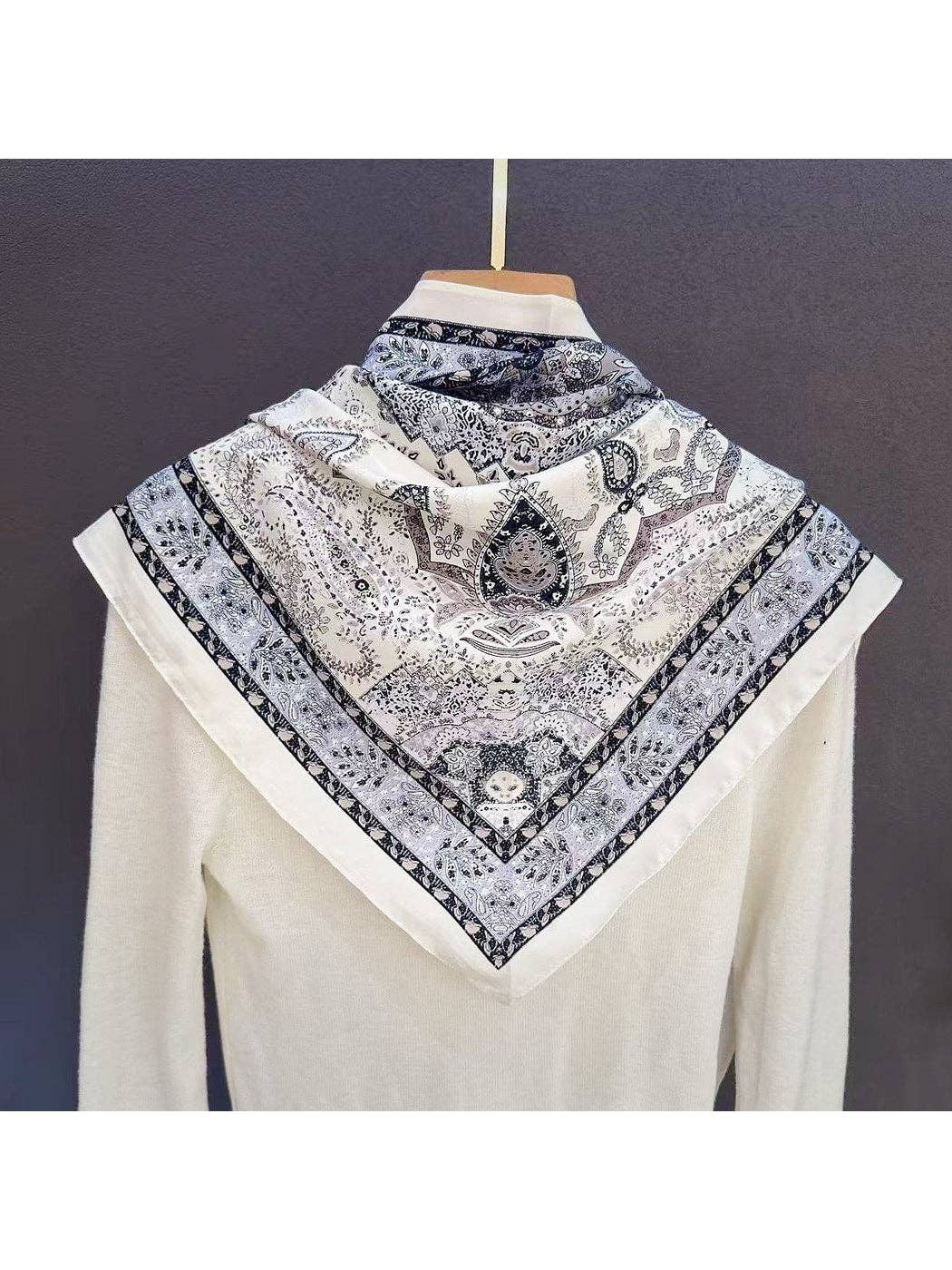 Muted grey triangle bandana scarf with vintage paisley pattern, folded near collar