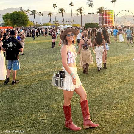 Woman in cowboy boots and a hat at a music festival with palm trees and a Ferris wheel in the background.