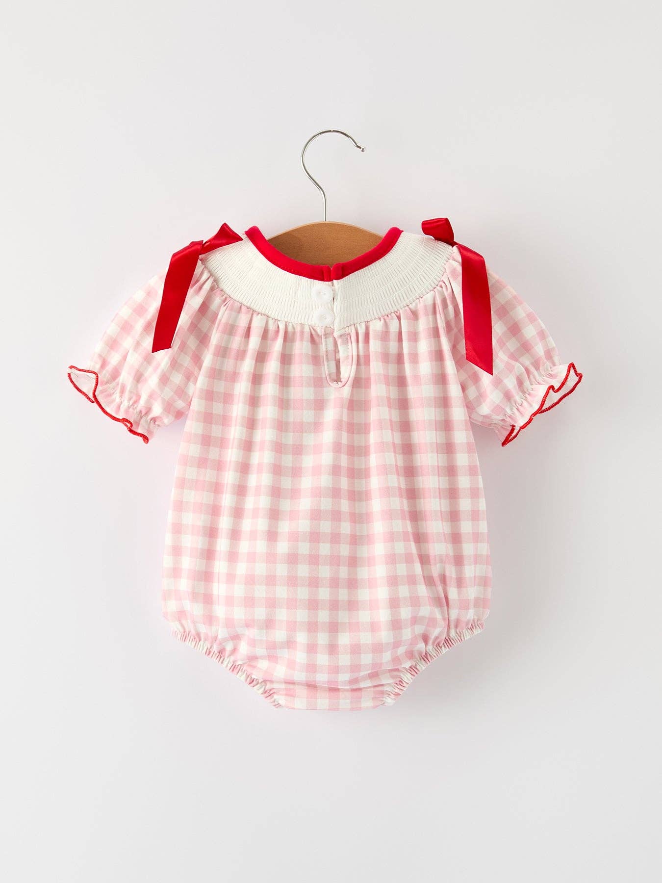 Pink checkered baby romper with red trim on a hanger against a white background