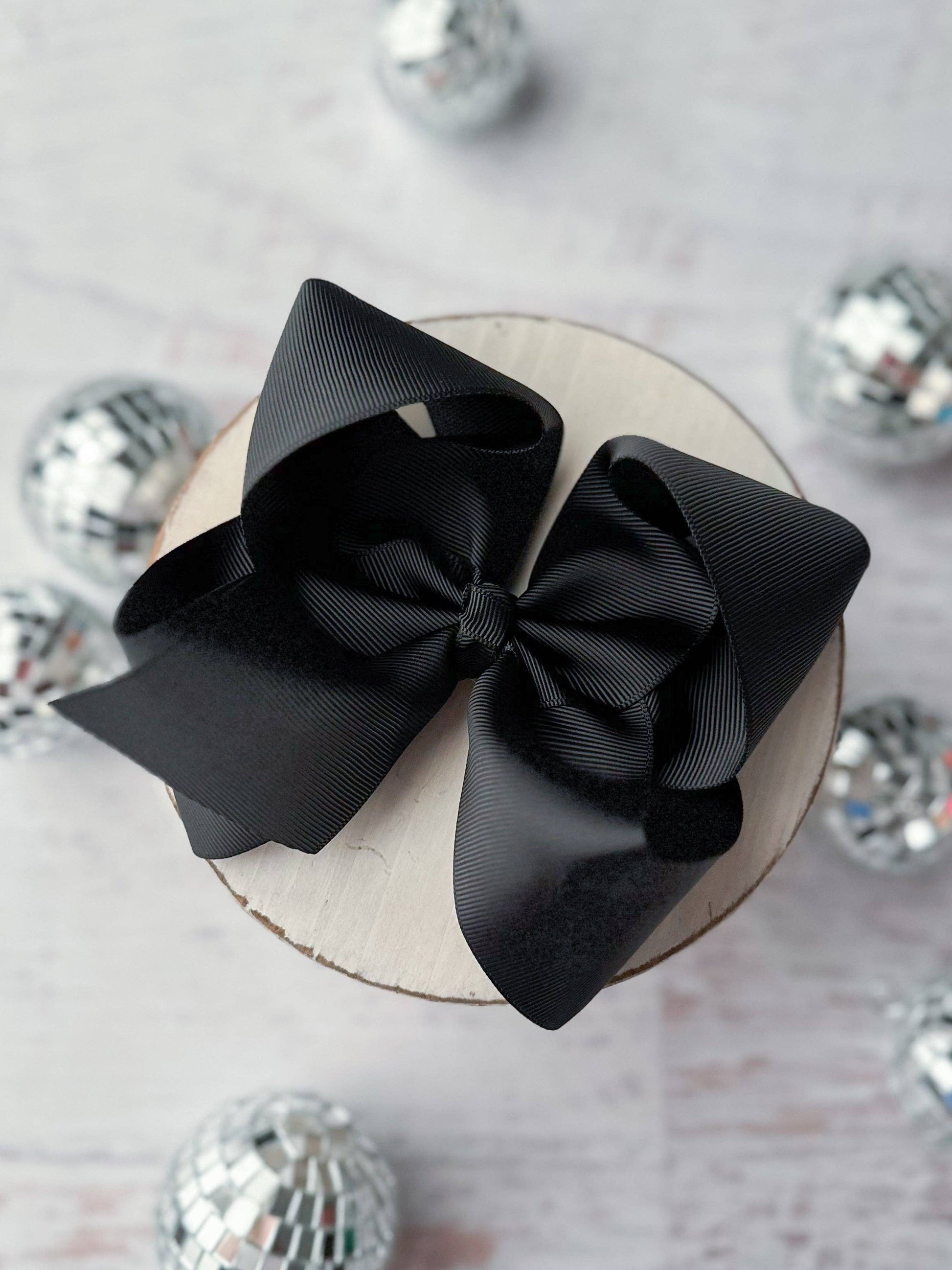 Black bow on a cake with disco balls in the background