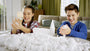 Two children playing with white cotton balls in a living room.