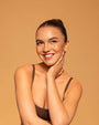 Woman wearing a brown strappy top against a beige background