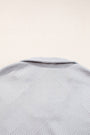 Close-up of a textured gray fabric with a subtle pattern on a light beige background