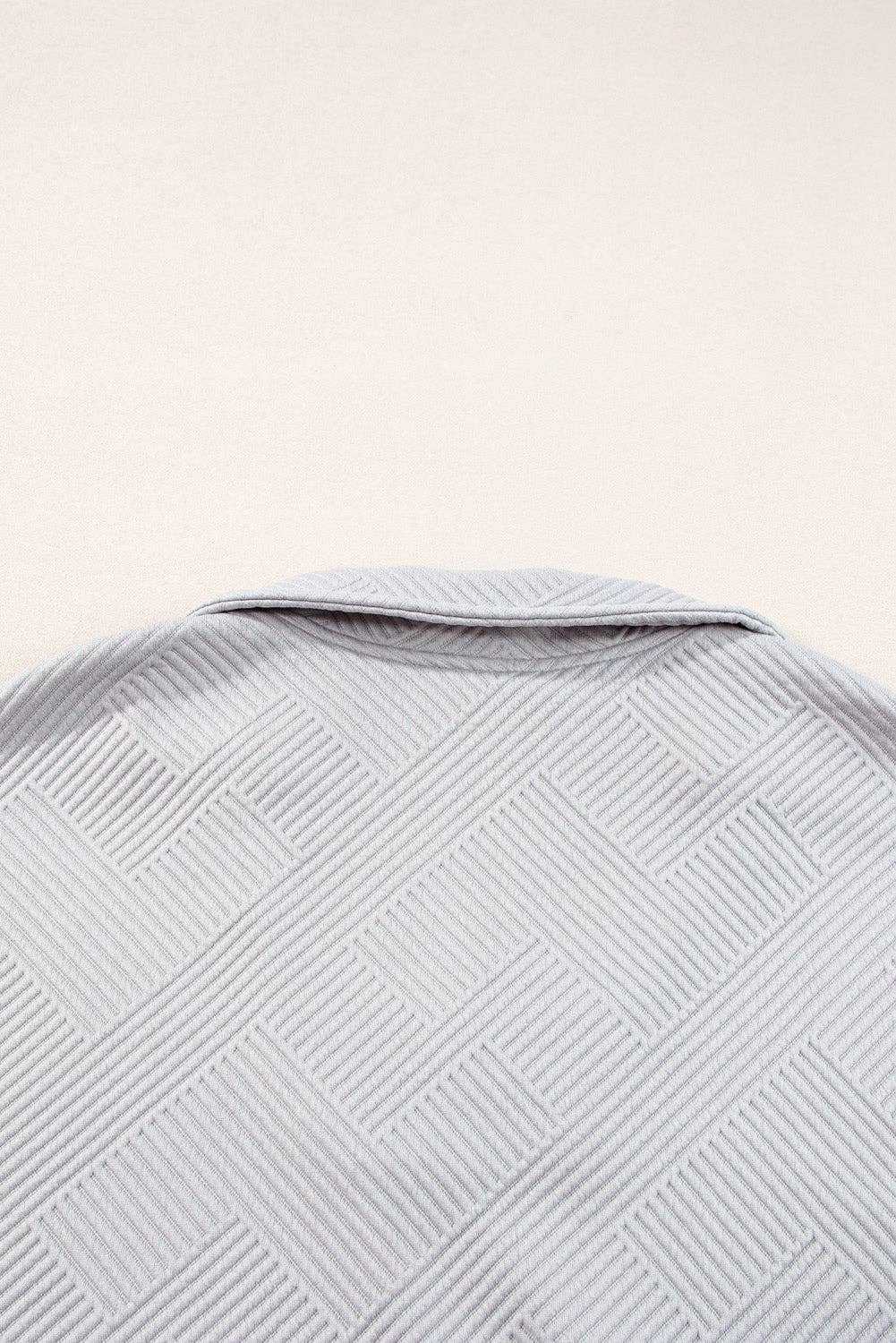 Close-up of a textured gray fabric with a subtle pattern on a light beige background