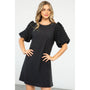 Woman wearing a black dress with ruffled sleeves against a white background