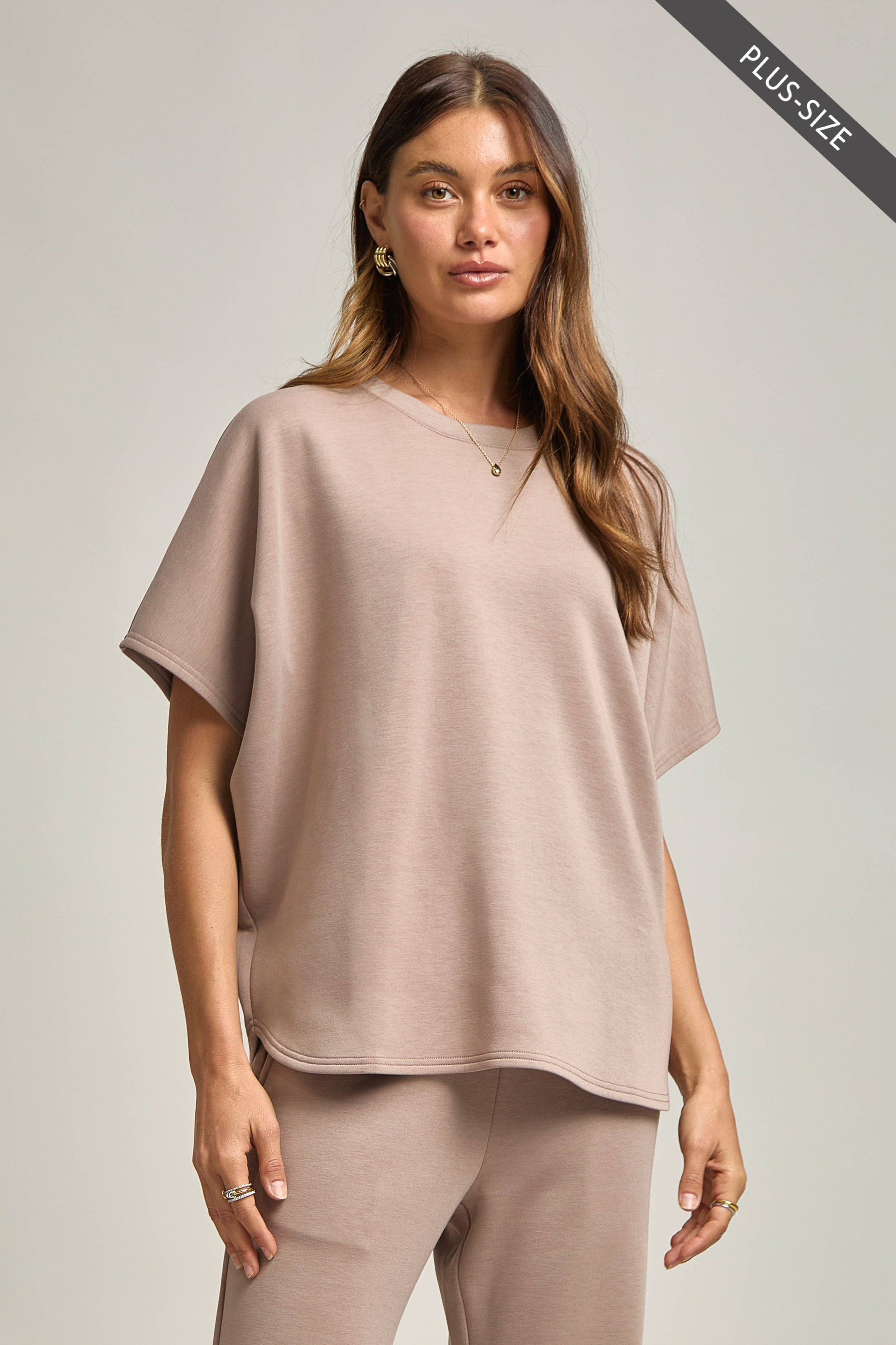 Woman wearing a beige plus-size outfit on a plain background