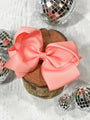 Two coral bows on a wooden block with disco balls in the background