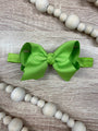 Green bow hair accessory on a wooden surface with wooden beads