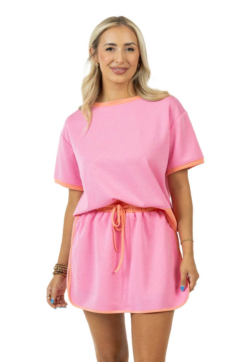 Woman wearing a pink outfit with orange trim on a white background
