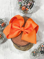 Orange bow on a wooden block with disco balls around it