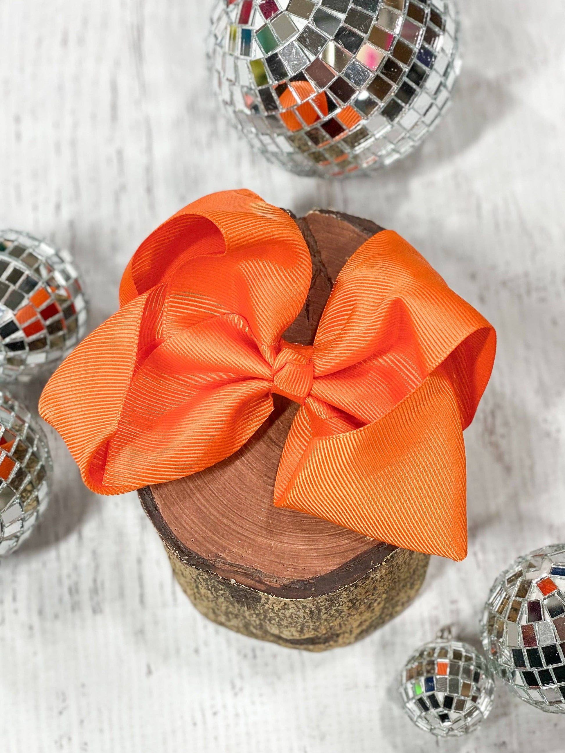 Orange bow on a wooden block with disco balls around it