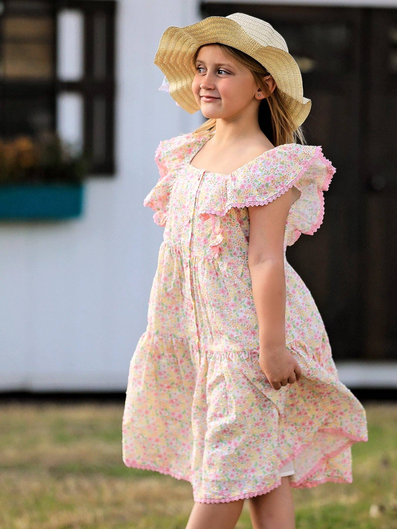 Young girl wearing a floral dress and straw hat outdoors