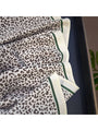 Leopard print bandana close-up with green-trimmed cream border and folded triangles