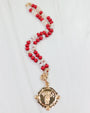 Necklace with red and white beads and a gold pendant on a white background
