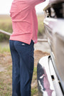 Person wearing a red striped shirt and navy pants standing next to a vehicle.