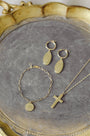 Gold jewelry set including bracelet, necklace, and earrings on a gray surface with a gold frame.