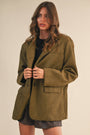 Woman wearing a green coat against a beige background