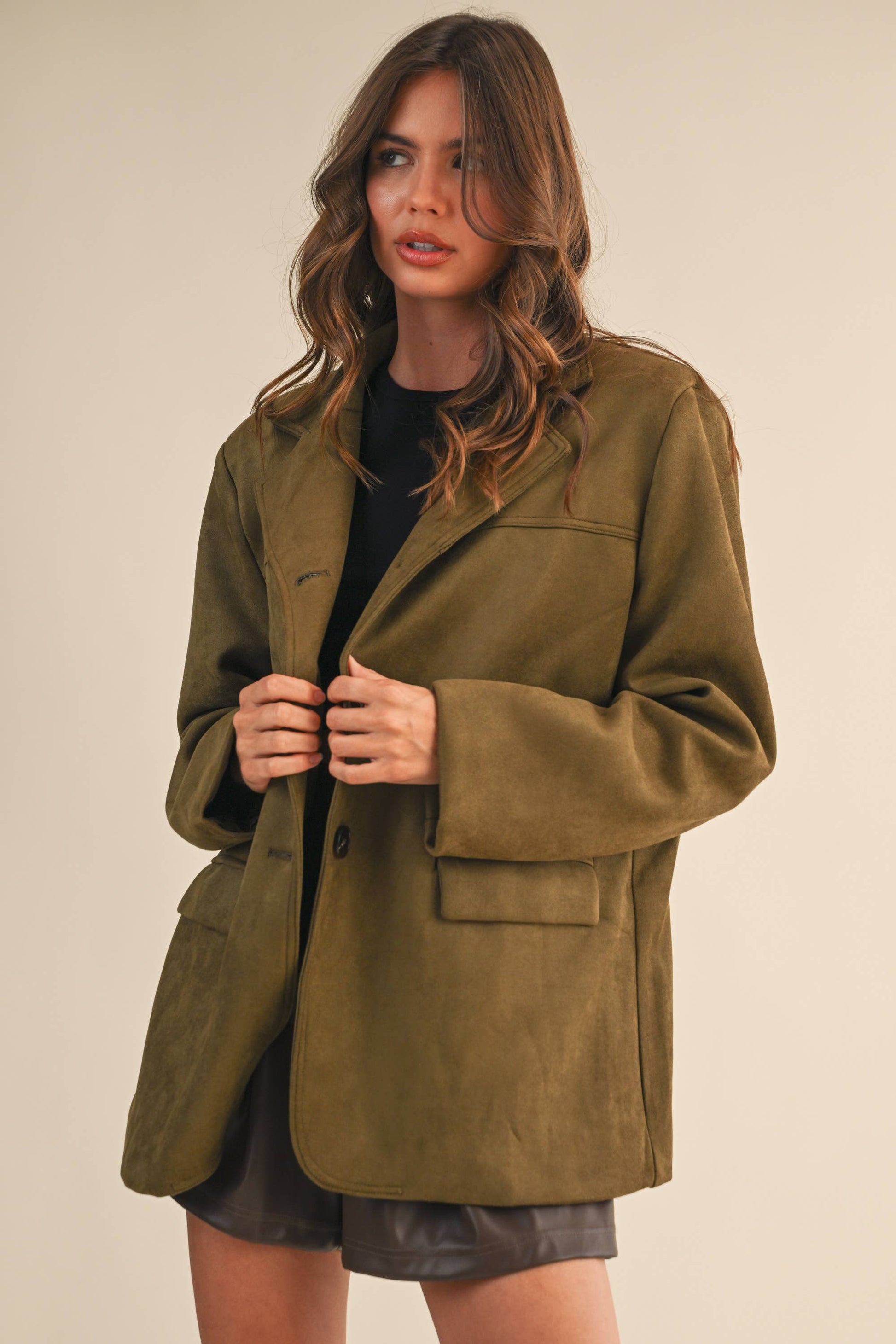 Woman wearing a green coat against a beige background