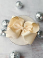 Small round box with a large beige bow on a light background