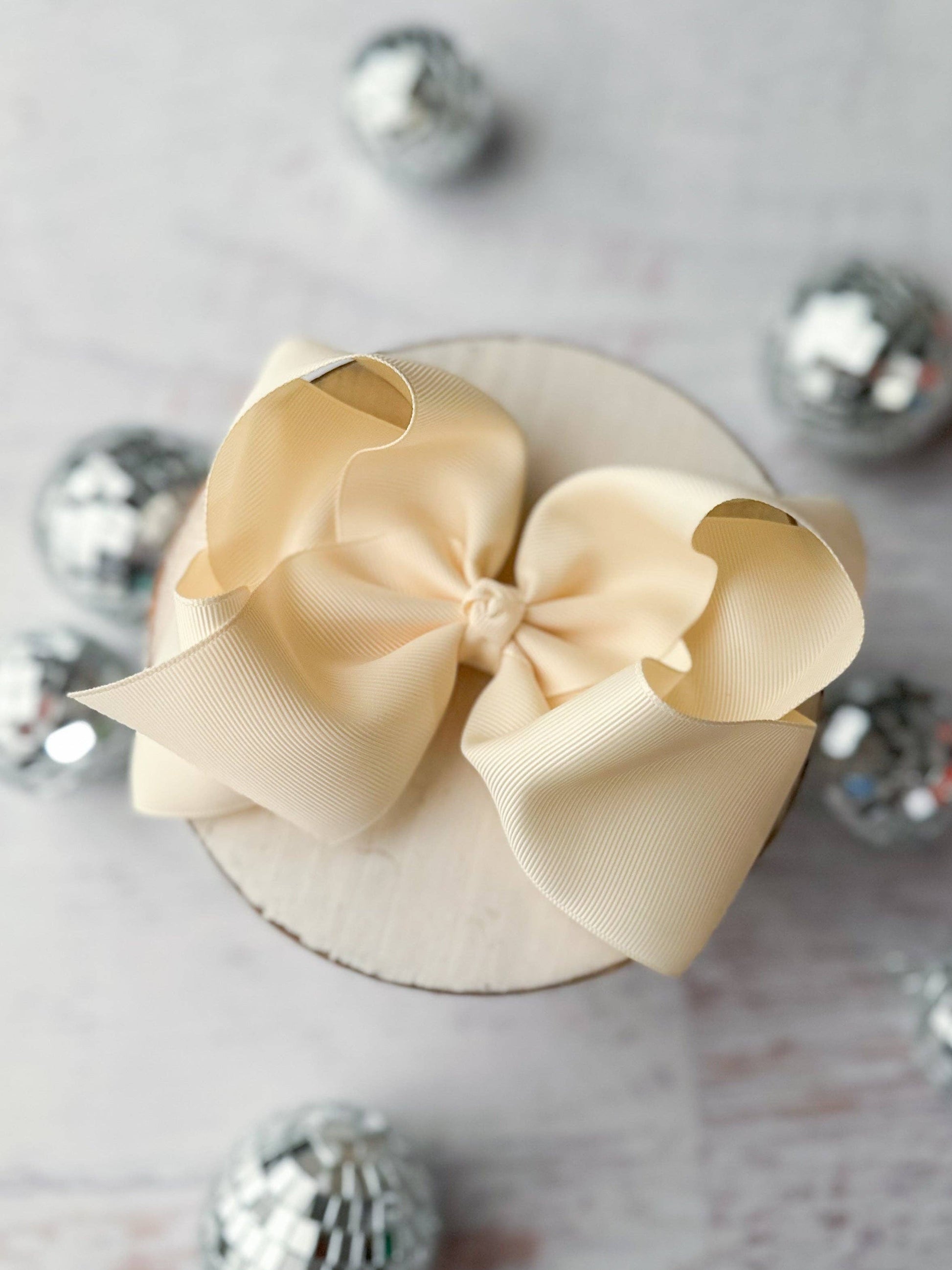 Small round box with a large beige bow on a light background