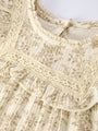 Close-up of a cream-colored lace garment with intricate patterns.