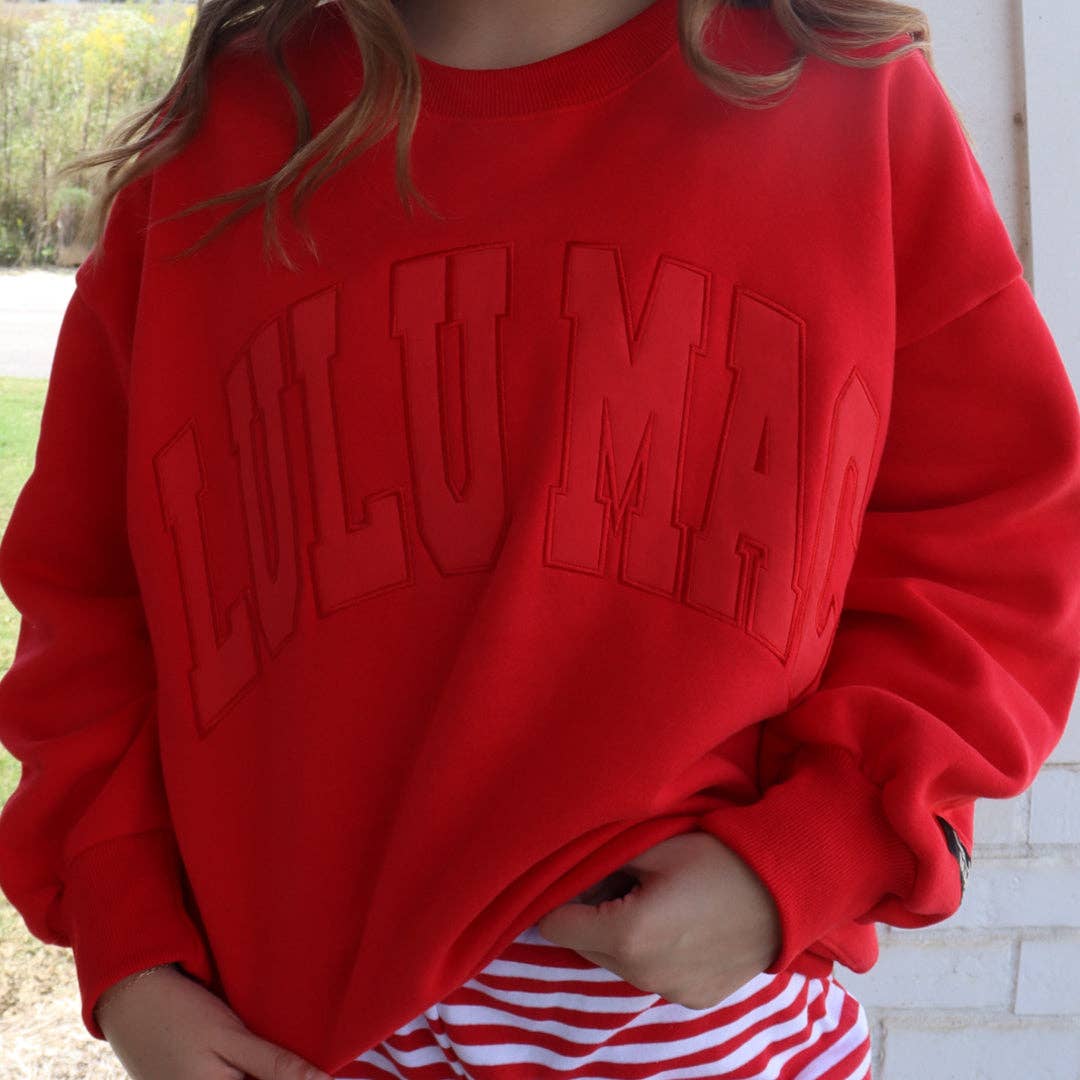 Red sweatshirt with 'ILLUMATI' text worn by a person, outdoor setting