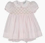 Pink baby dress with lace details on a white background