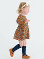 Child wearing a colorful floral dress with navy socks and orange shoes on a white background