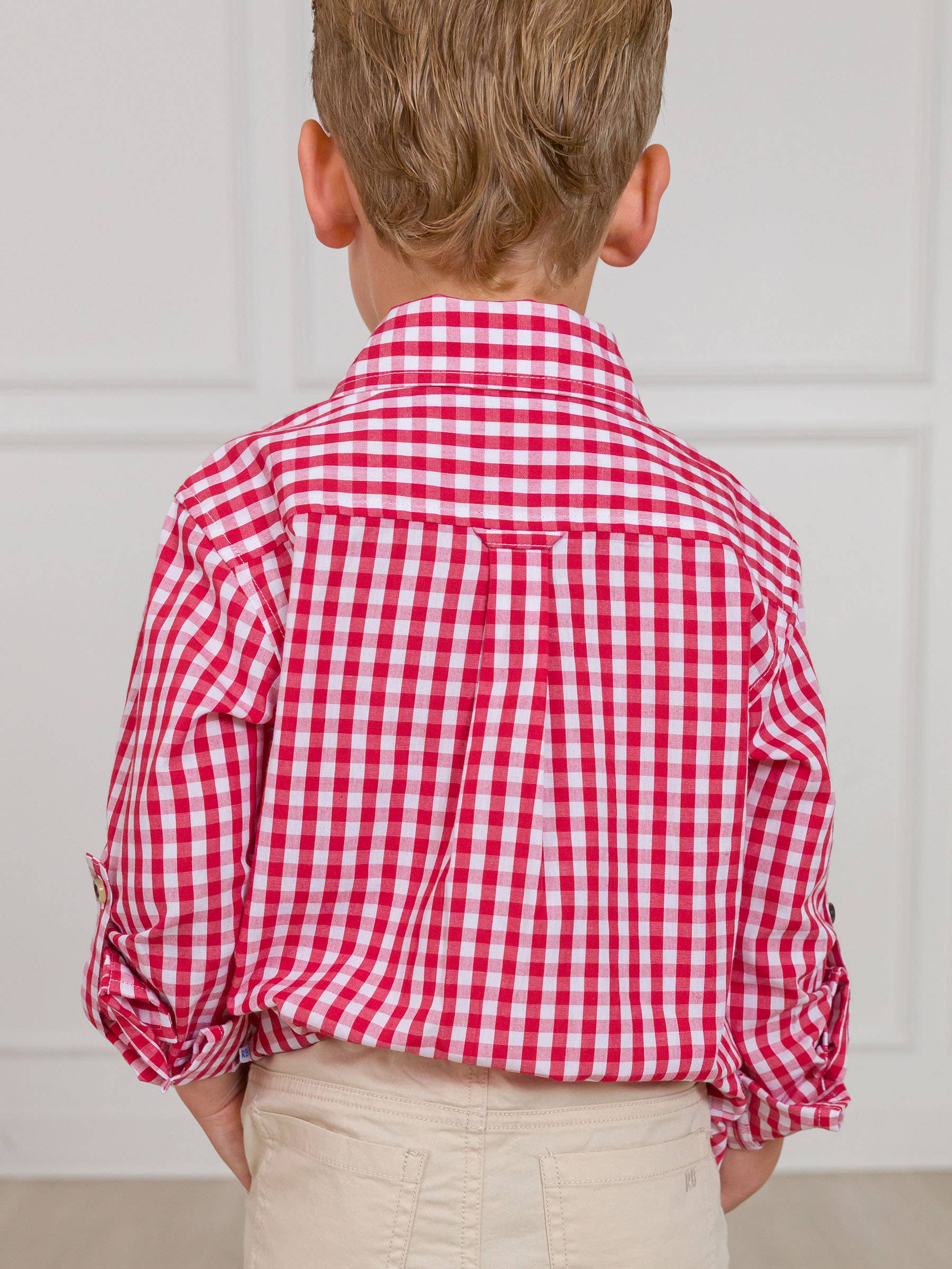 Child wearing a red and white checkered shirt against a plain background