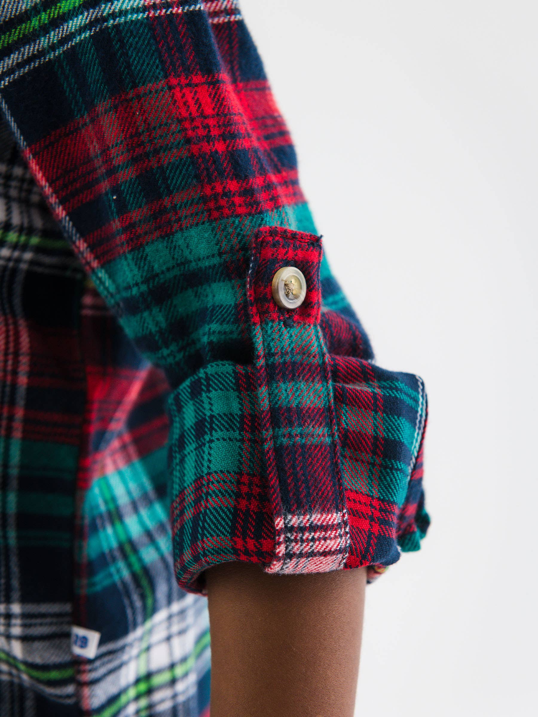 Close-up of a plaid shirt with a button on a white background