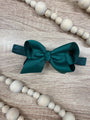 Teal bow on a wooden surface with white beads