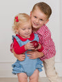 Two children, a boy and a girl, standing close together with a white background.