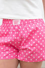 Pink polka dot shorts with 'Lulu Mac' branding worn by a person.