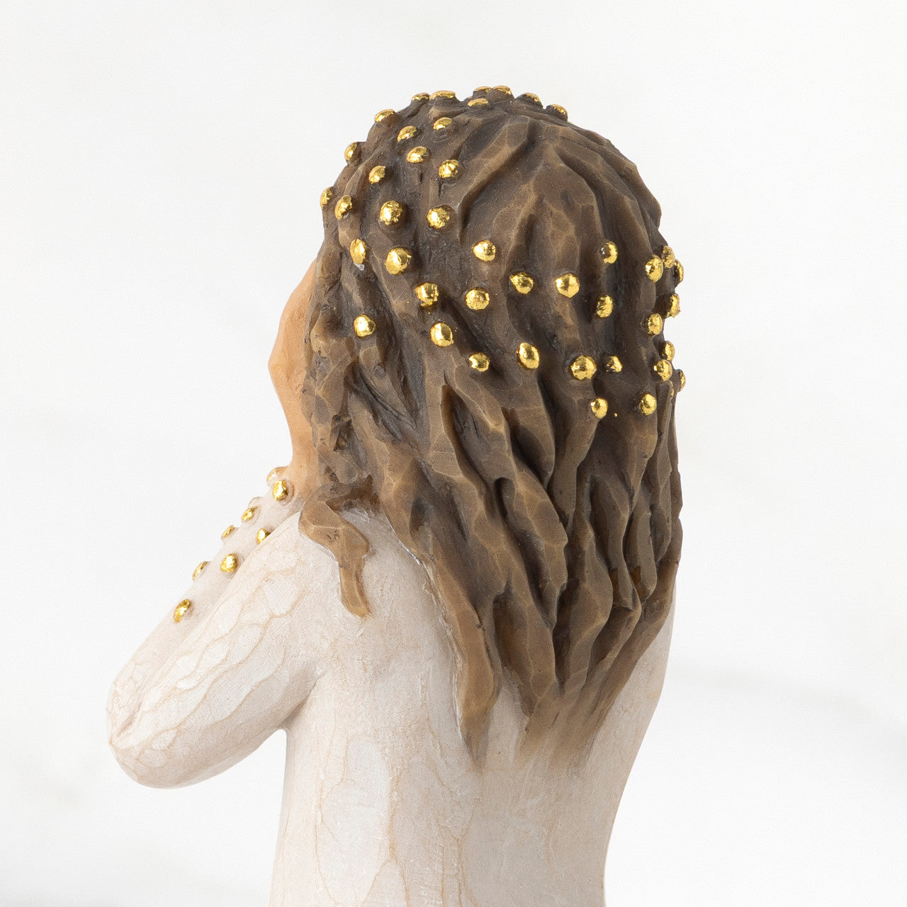 Statue of a woman with braided hair and gold beads on a white background