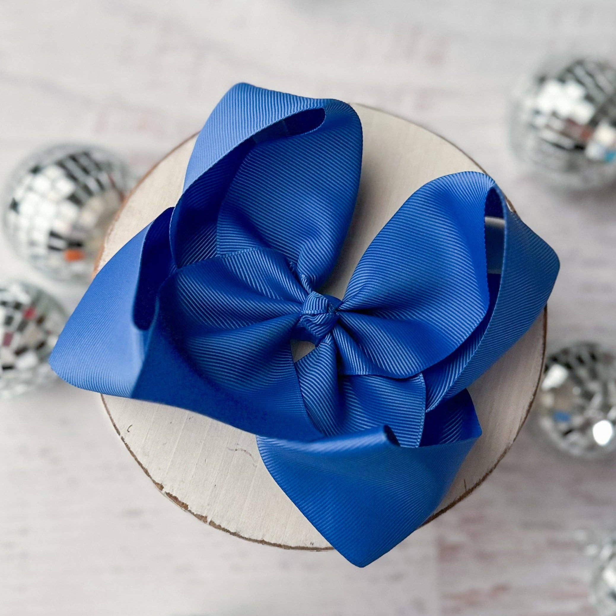 Blue bow on a white cake with silver disco balls in the background