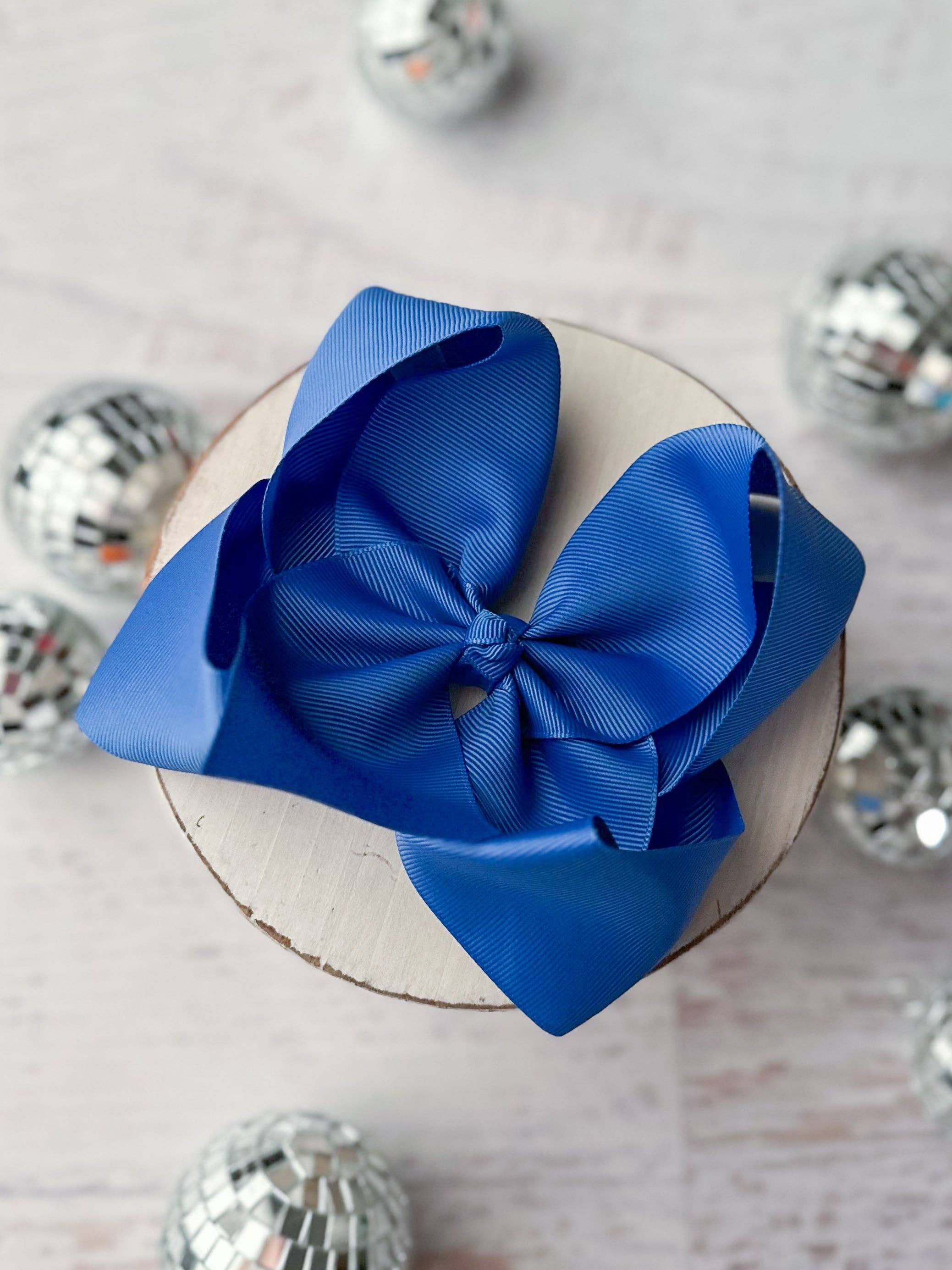Blue bow on a white cake with silver disco balls in the background