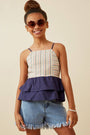 Young girl wearing a striped top and denim shorts with sunglasses on a beige background