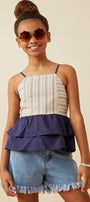 Young girl wearing a striped top and denim shorts with sunglasses on a beige background