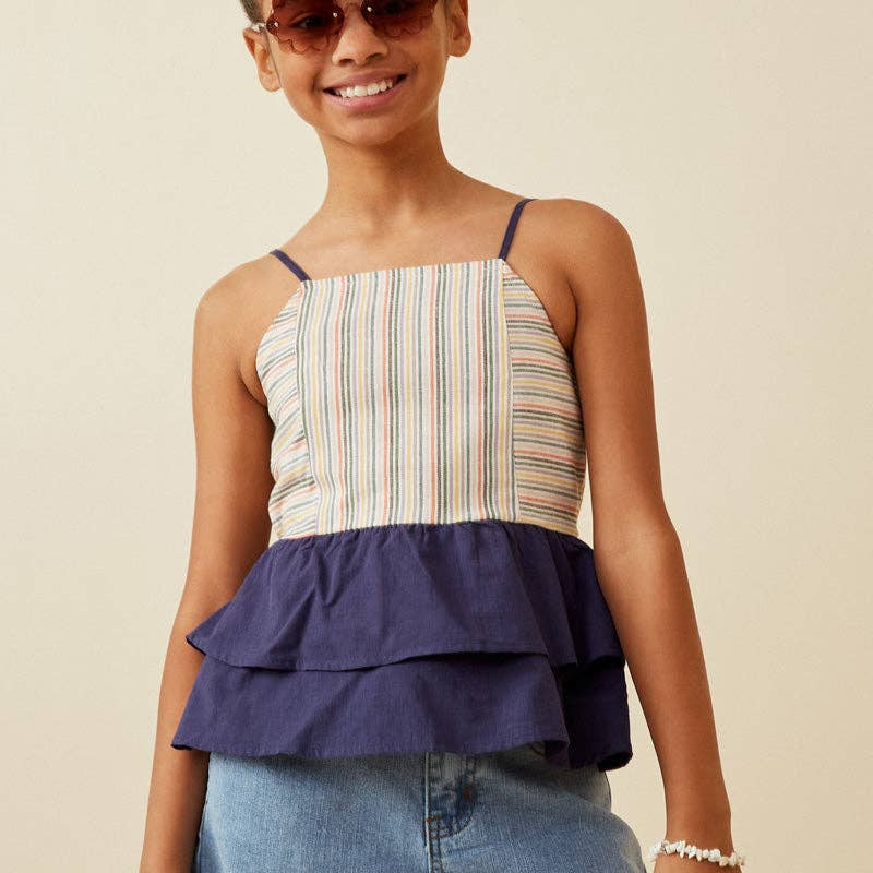 Young girl wearing a striped top and denim shorts with sunglasses on a beige background