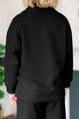 Person wearing a black textured jacket and pants in an indoor setting