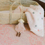 Small doll and soft blanket with polka dots next to a woven basket on a patterned surface