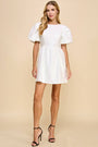 Woman wearing a white dress with puffed sleeves on a beige background