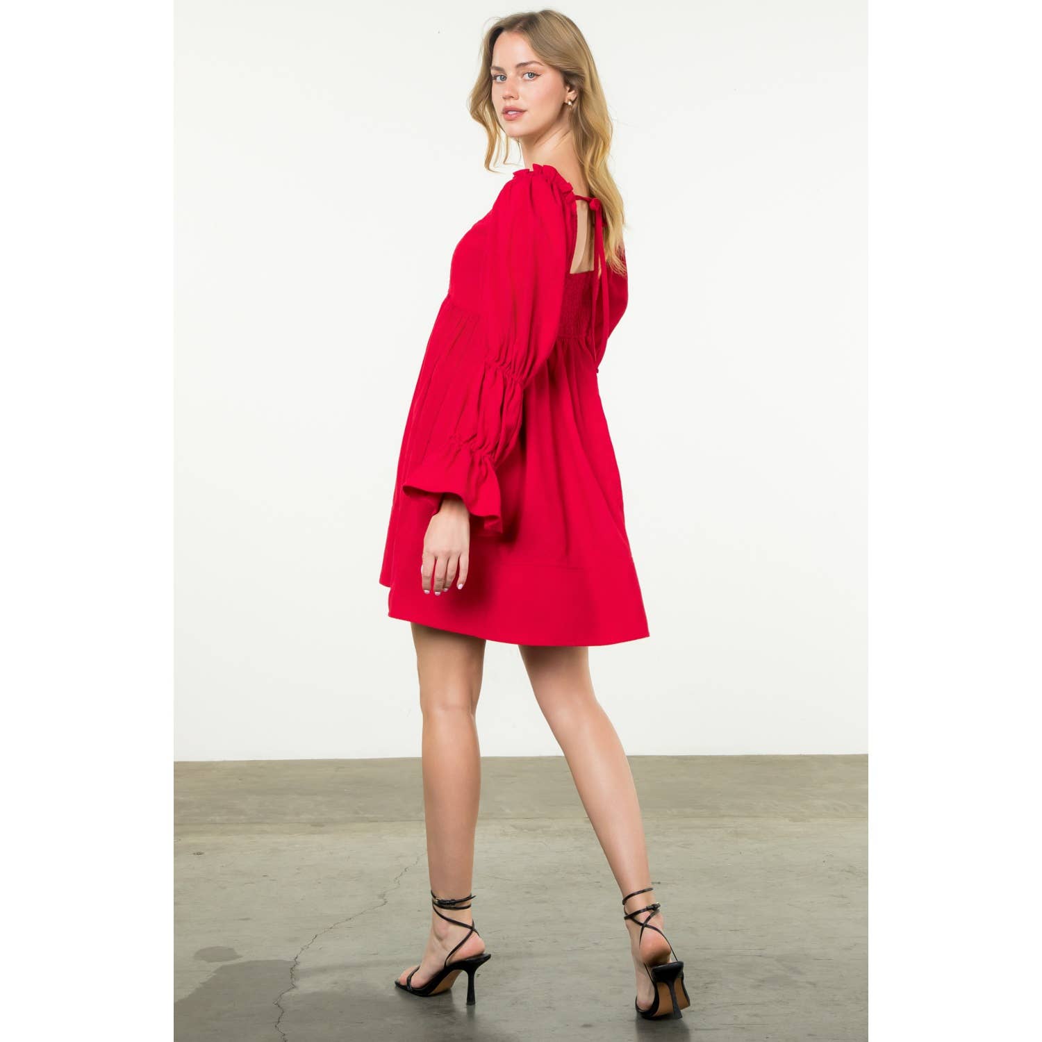 Woman wearing a red dress with long sleeves on a white background