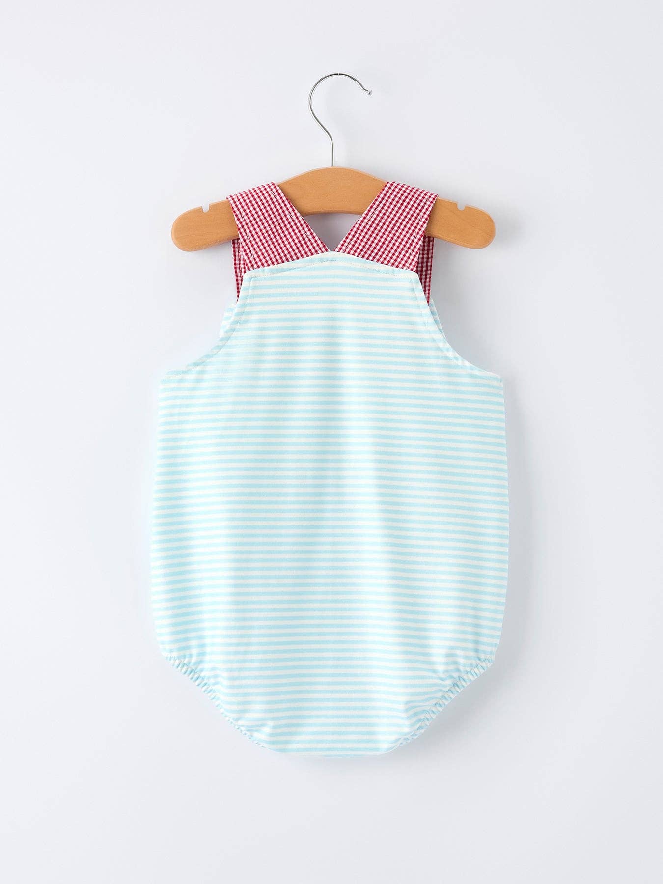 Baby romper with red checkered top and blue striped bottom on a hanger against a white background