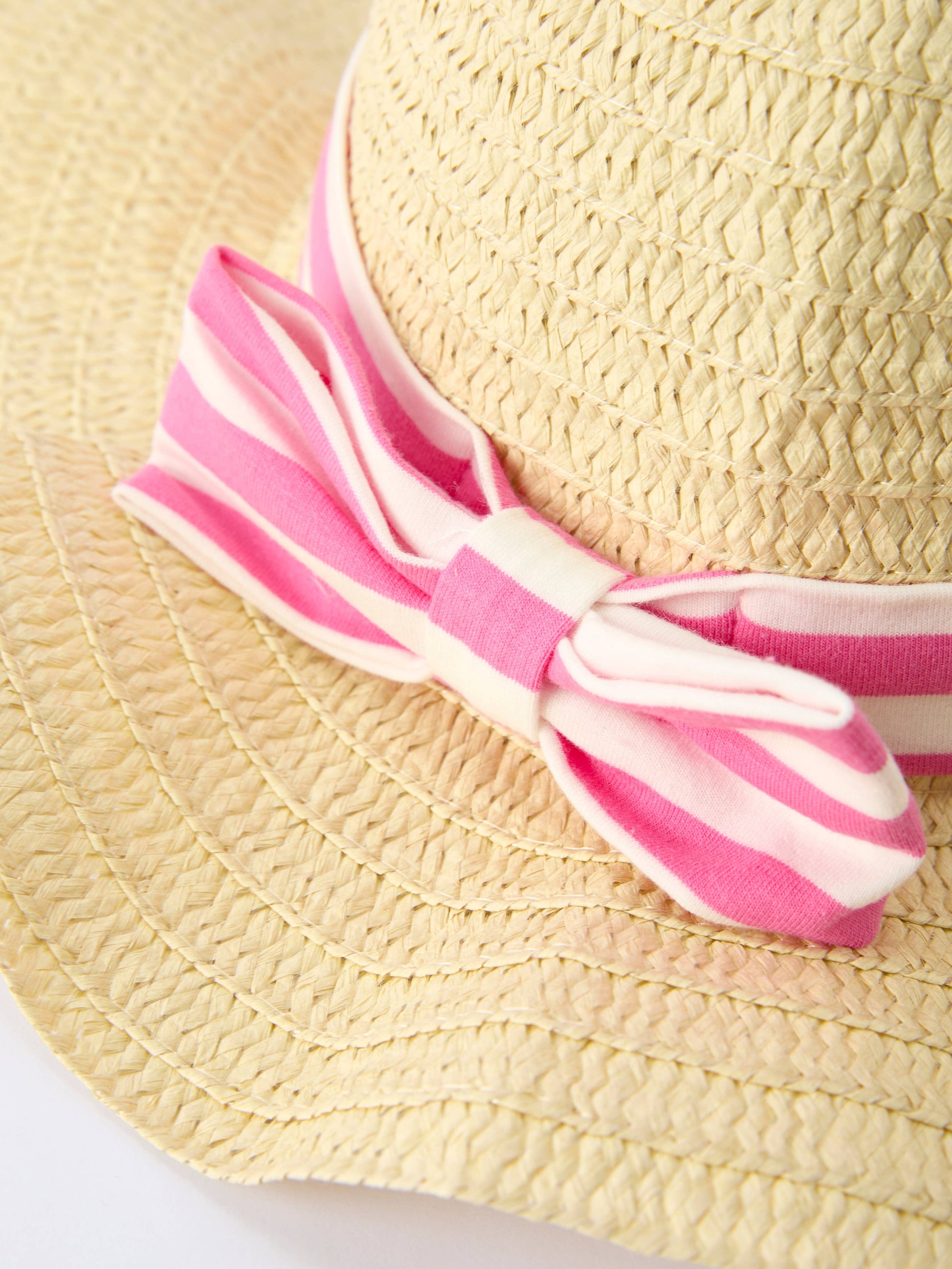 Straw hat with a pink and white striped ribbon on a light background